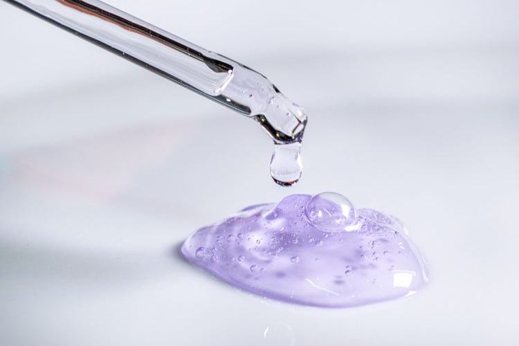Pipeta soltando una gota de gel morado, concepto de laboratorio y cuidado de la piel